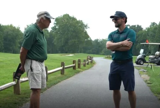 Host talking with a golfer on the cart path